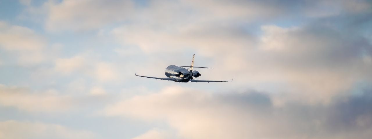 a private jet flying away above the clouds 