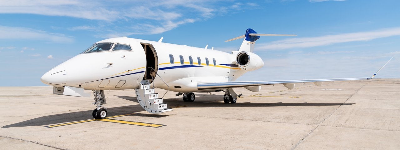 A private jet parked on the tarmac with its stairs down.