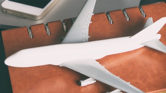 White model airplane on a brown leather book