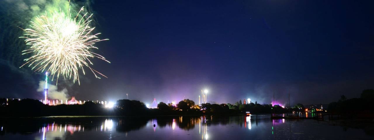 the fireworks in the sky by the river at night.