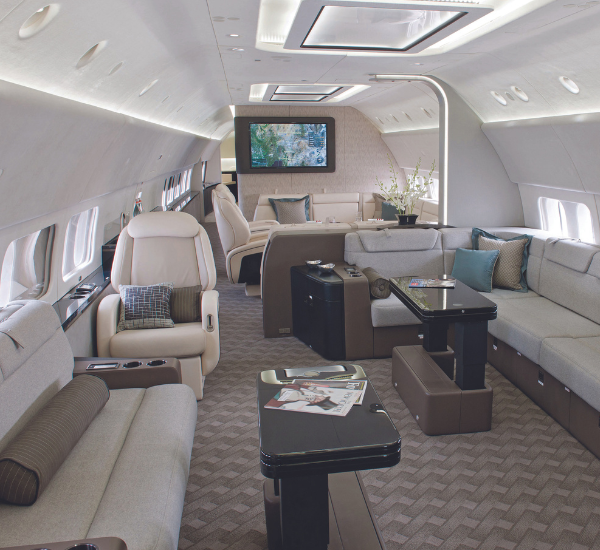 A spacious lounge on an executive jet with a flat-screen TV and seating.