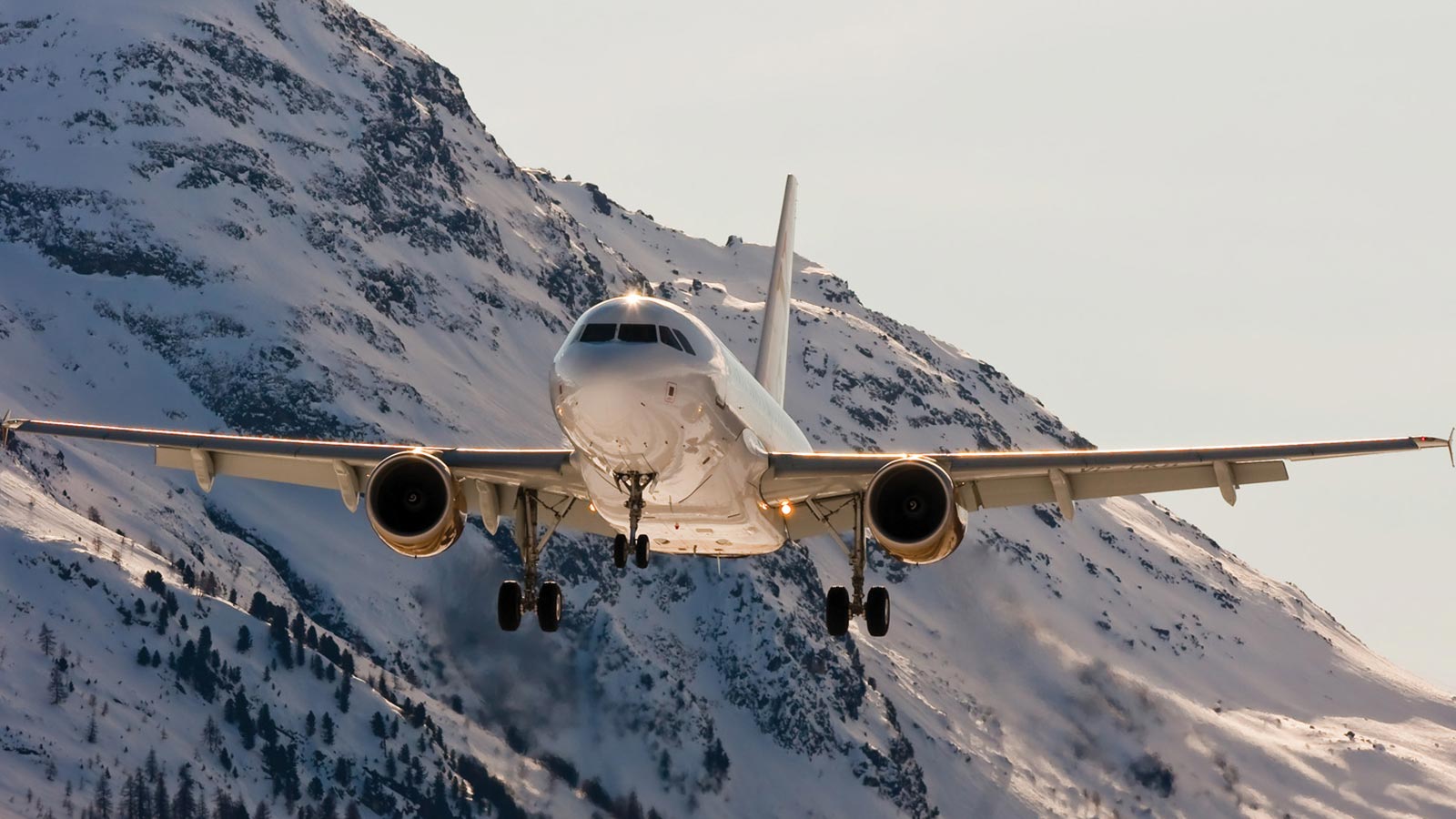 An Airbus A318 Elite taking off with a snowy mountain in the background.