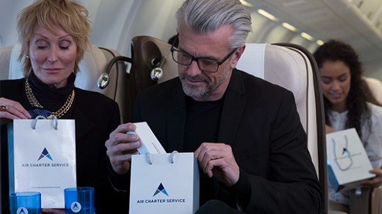 A man and a woman on a plane looking at True Sky Charter Services gift bags